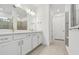 Bathroom with double vanity, white cabinets, quartz counters, and a glass-enclosed shower at 11447 Shoreline Trl, Parrish, FL 34219