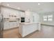 Modern kitchen with white cabinets, stainless steel appliances, a large island, and wood flooring at 11447 Shoreline Trl, Parrish, FL 34219