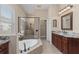 Elegant bathroom with a soaking tub, walk-in shower, dual vanities, and natural light at 12610 Eagles Entry Dr, Odessa, FL 33556