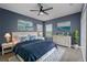 Blue bedroom featuring a queen bed with a patterned comforter, ocean paintings, and a modern ceiling fan at 12610 Eagles Entry Dr, Odessa, FL 33556