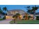 Elegant two-story home with manicured lawn, mature palms, and a tile roof at 12610 Eagles Entry Dr, Odessa, FL 33556