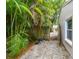 Side yard with lush tropical foliage, wooden fence, and pebbled groundcover at 130 41St Ne Ave, St Petersburg, FL 33703