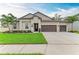 Charming home featuring a three-car garage, a well-maintained lawn, and mature palm trees at 13034 Bliss Loop, Bradenton, FL 34211