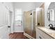 Bathroom featuring a tile shower with glass door, wood floors, and vanity at 15045 Wind Whisper Dr, Odessa, FL 33556