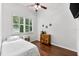 Bright bedroom with hardwood floors, ceiling fan, window with plantation shutters, and wooden cabinet at 15045 Wind Whisper Dr, Odessa, FL 33556