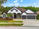 Charming two-story home featuring gray accents, manicured landscaping, arched entryway, and a three-car garage at 15045 Wind Whisper Dr, Odessa, FL 33556