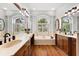 Bright bathroom with dual sinks, wood cabinets, and a soaking tub with a large window at 15045 Wind Whisper Dr, Odessa, FL 33556