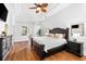 Spacious main bedroom with a dark wood bed frame, tray ceiling and hardwood floors at 15045 Wind Whisper Dr, Odessa, FL 33556