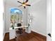 Bright office featuring a modern desk, dark wood floors, high ceilings, and a large window with white shutters at 15045 Wind Whisper Dr, Odessa, FL 33556