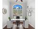 Minimalist office featuring a modern desk, dark wood floors, high ceilings, and a large window with white shutters at 15045 Wind Whisper Dr, Odessa, FL 33556