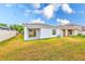 Spacious backyard with green and golden grass, sliding glass door, and white fence at 15410 Quail Woods Pl, Ruskin, FL 33573