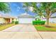Charming home exterior featuring a two-car garage, well-maintained landscaping, and a manicured lawn at 15410 Quail Woods Pl, Ruskin, FL 33573