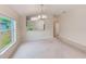 Open-concept living room with view of the kitchen, plush carpet, and natural light from a window at 15410 Quail Woods Pl, Ruskin, FL 33573