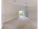 Neutral living room with plush carpet, view to the backyard through sliding doors, and ceiling fan at 15410 Quail Woods Pl, Ruskin, FL 33573
