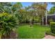 Landscaped backyard featuring a lush lawn, mature trees, and a secure metal fence at 16522 Ivy Lake Dr, Odessa, FL 33556