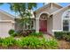 Inviting front exterior featuring a red door, mature landscaping, and a neutral exterior at 16522 Ivy Lake Dr, Odessa, FL 33556