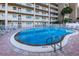 Community pool area with plenty of seating, umbrellas, and palm trees at 18650 Gulf Blvd # 601, Indian Shores, FL 33785