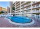 Community pool area with ample seating, sun umbrellas, and lush palm trees at 18650 Gulf Blvd # 601, Indian Shores, FL 33785