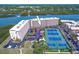 Aerial view of condos featuring a parking lot, well-kept landscaping and a tennis court at 19451 Gulf Blvd # 211, Indian Shores, FL 33785