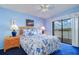 Comfortable bedroom featuring blue walls, patterned bedding, and sliding glass doors with balcony access at 19451 Gulf Blvd # 211, Indian Shores, FL 33785