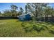 Spacious backyard with a blue shed, lush green lawn, and mature trees offering ample shade at 1965 Allard Dr, Clearwater, FL 33763