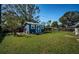 Charming backyard shed painted blue with white trim surrounded by a lush green lawn and garden at 1965 Allard Dr, Clearwater, FL 33763