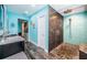 Modern bathroom featuring a walk-in shower with blue tile accents, river rock flooring and a dark vanity at 1965 Allard Dr, Clearwater, FL 33763