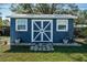 Close up of backyard shed painted blue with white trim with a stone walkway and garden at 1965 Allard Dr, Clearwater, FL 33763