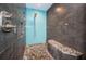 Modern walk-in shower with stone floors, a built-in bench, and beautiful blue tile accents at 1965 Allard Dr, Clearwater, FL 33763