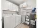 Bright laundry room with white washer, dryer, overhead cabinets, and water heater at 2511 W Braddock St, Tampa, FL 33607