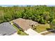An aerial view showcases a home with a manicured lawn and a driveway, situated next to a wooded area at 26249 Sword Dancer Dr, Wesley Chapel, FL 33544