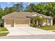 Charming single-story home featuring a well-maintained lawn, mature trees, and a three-car garage at 26249 Sword Dancer Dr, Wesley Chapel, FL 33544