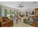 Open-concept living room with tile floors, ceiling fan, view of the backyard and kitchen at 26249 Sword Dancer Dr, Wesley Chapel, FL 33544