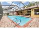 A refreshing screened-in pool with bar area and brick patio offers the perfect spot for outdoor entertaining and relaxation at 2664 Frisco Dr, Clearwater, FL 33761
