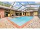 Enjoy outdoor living with a sparkling screened-in pool, brick patio, and a tranquil setting perfect for entertaining at 2664 Frisco Dr, Clearwater, FL 33761
