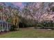Large backyard featuring lawn, tropical plants, and mature trees with a pond at 3728 Cypress Meadows Rd, Tampa, FL 33624