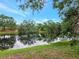 Scenic view of the calm pond surrounded by mature trees on a sunny day at 3728 Cypress Meadows Rd, Tampa, FL 33624