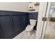 Half bath featuring navy wainscoting, marble flooring, and modern toilet at 414 Finn Way # 4, Dunedin, FL 34698