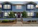Charming blue townhome featuring a red door, white trim, and a landscaped front yard with a decorative fence at 414 Finn Way # 4, Dunedin, FL 34698