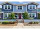 Charming blue townhome featuring a red door, white trim, and a landscaped front yard with a decorative fence at 414 Finn Way # 4, Dunedin, FL 34698