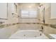 Relaxing bathroom featuring a tub with decorative tile and a window with shutters at 4161 Rolling Springs Dr, Tampa, FL 33624