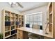 Bright home office featuring custom built-ins, a large desk, neutral colors, and natural light from a large window at 4161 Rolling Springs Dr, Tampa, FL 33624