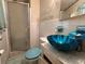 Unique bathroom with a blue vessel sink, a glass-enclosed shower, and decorative wallpaper at 459 Bayview Ne Dr, St Petersburg, FL 33704