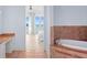 Luxurious bathroom with a soaking tub, dual vanity area, and serene views from the French doors at 6106 Marbella Blvd, Apollo Beach, FL 33572