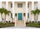 Elegant front entrance with a striking teal door, complimented by manicured landscaping and stately columns at 6106 Marbella Blvd, Apollo Beach, FL 33572