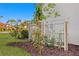 Close-up of garden with decorative trellis, young trees, fresh mulch, and lush green grass against a white building at 6106 Marbella Blvd, Apollo Beach, FL 33572