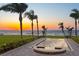Sunset view of a sleek pool facing the ocean, framed by palm trees and manicured landscaping at 6106 Marbella Blvd, Apollo Beach, FL 33572