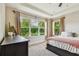 Bright main bedroom featuring a tray ceiling, large windows, and a view of lush greenery at 6642 Current Dr, Apollo Beach, FL 33572