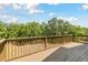 Wide balcony with wooden railings, offering views of the surrounding trees and open space at 7606 Four Pines Rd, Plant City, FL 33565