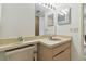 Tan bathroom featuring a single sink, vanity, and a large mirror with decorative lighting at 7606 Four Pines Rd, Plant City, FL 33565